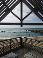 Looking over the calm waters of the Le Croisic beach thought a symmetrical view from a beach shed