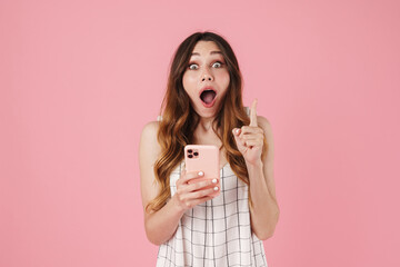 Image of shocked cute woman using cellphone and pointing finger upward