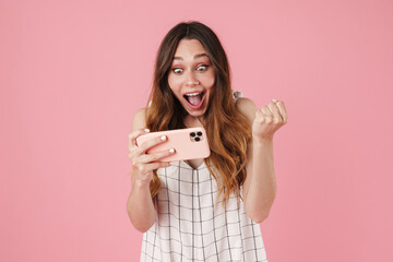 Naklejka premium Image of excited cute woman using cellphone and making winner gesture