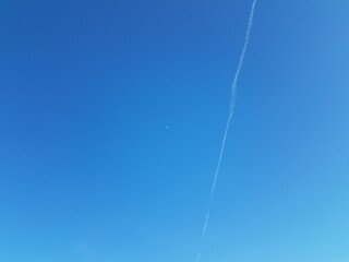moon and contrail or cloud in blue sky