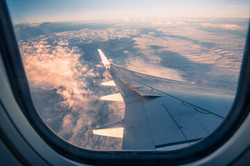 Silhouette wing of an airplane at sunrise view through the window.