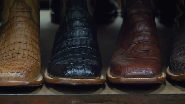 Cowboy boots on a shelf in a store, facing straight. Cowboy boots on sale on a shelf in the store indoors. American-style boots from ostrich, crocodile and buffalo leather. Cowboy boot on the shelf.