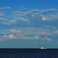 Naklejka na ściany i meble A ship at sea on a background of blue sky. Curonian Spit.