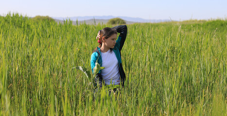 Naklejka na ściany i meble teen girl in a green grass field in summer
