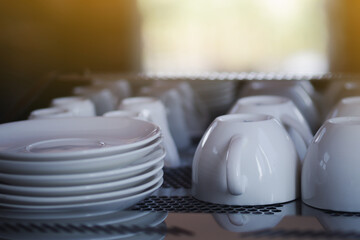 Close-up of white coffee cups and saucers are placed upside down on top the the coffee maker