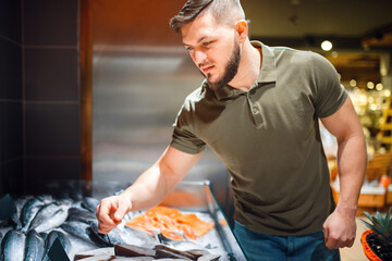 Man choosing fresh chilled fish in grocery store