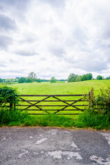 Fototapeta na wymiar Wooden gate with open field and hawthron hedge