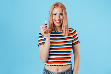 Image of happy caucasian girl smiling at camera and holding lipstick