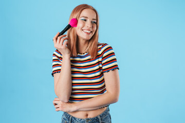 Image of excited girl smiling at camera and using powder brush