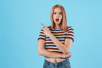 Image of shocked girl in striped t-shirt pointing fingers aside