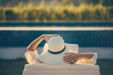 Summer vacation concept, Asian woman with white hat relax in hotel resort and swiming pool in...