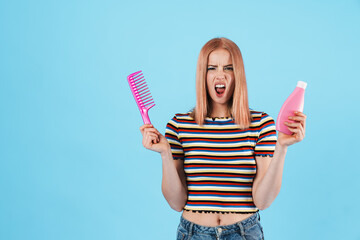 Image of furious charming girl showing shampoo and comb