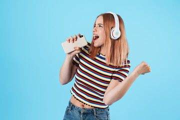 Image of girl singing while using wireless headphones and cellphone