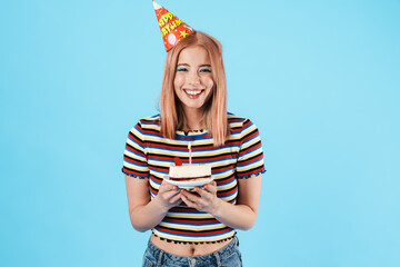 Image of cheerful nice girl in party cone holding cake and laughing
