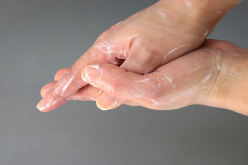 Sparkling hands with a white natural soap on a gray background. The importance of hand washing in quarantine days. Hands washed with plenty of foam to protect against coronavirus.