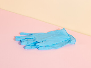 Blue medical gloves on yellow pink background. The concept of protection against disease. Copy space.