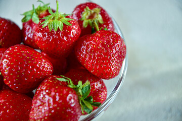 Glass bowl with ripe strawberries. Side view. Close-up.