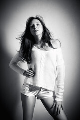 Fototapeta premium Monochrome fashion portrait of an attractive young woman wearing white pullover and shorts