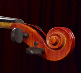 violin neck on dark curtains background. wooden classical musical instrument detail