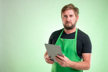 Supermarket employee with greenapron and black t-shirt takes notes