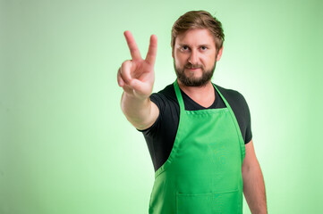 Fototapeta premium Supermarket employee with green apron showing victory