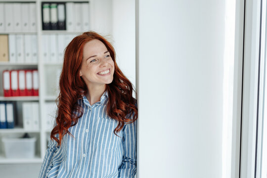 Young smiling red-haired woman in office
