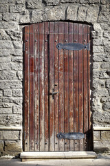 Atmospheric wooden door with shabby paint in the stone wall of the house