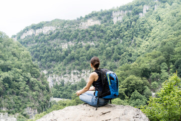 Naklejka na ściany i meble Young woman hiking with a backpack in solitude with herself high in the mountains. Restoring welbeing of mind in nature in silence.