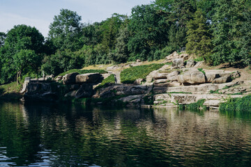 Fototapeta na wymiar Sofia Park, Uman. Beautiful summer park with a lake, tall trees, large stones and statues. Lake with large stones. Lake among the national park.