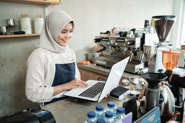 Obraz na płótnie Canvas Cafe owner hijab women use laptops to check supplies of raw materials
