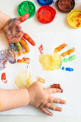 Close up of colored hand print on white background. Ideas for drawing with finger paints. Finger painting for kids. Little girl painting by finger hand paint color. Children development concept.