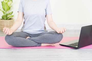 Naklejka premium Young beautiful asian woman doing training fitness workout sport exercise feel no stress free, using laptop while sitting on floor watches a yoga tutorial at screen at home on self