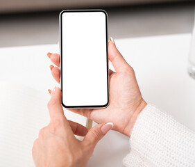 Hands of adult woman are holding smartphone with empty screen