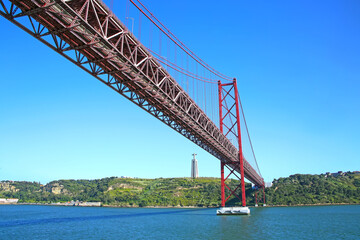 25 de Abril suspension Bridge connecting the city of Lisbon, to the municipality of Almada & the statue of Christ on the banks of the Tejo Estuary, Lisbon, Portugal.