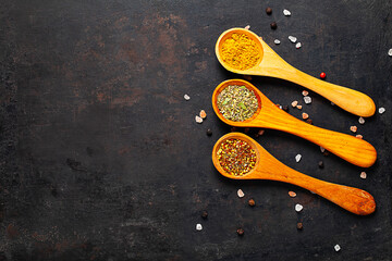 Dried spices in spoons on textured background