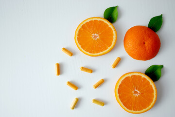 Vitamin C capsules and slices of orange citrus fruit with copy space. Natural supplements, antioxidants, prevention, immunity, detox concept.