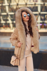 Body length outdoor portrait of young elegant woman wearing casual pullover, trousers and coat with...