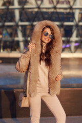 Body length outdoor portrait of young elegant woman wearing casual pullover, trousers and coat with...