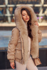 Cute pretty woman outdoor winter portrait in warm coat with fur hood. Stylish fashionable woman...