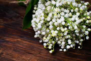 Delicate bouquet of lily of the valley on a wooden table. Bouquet for the holiday. Selective focus.
