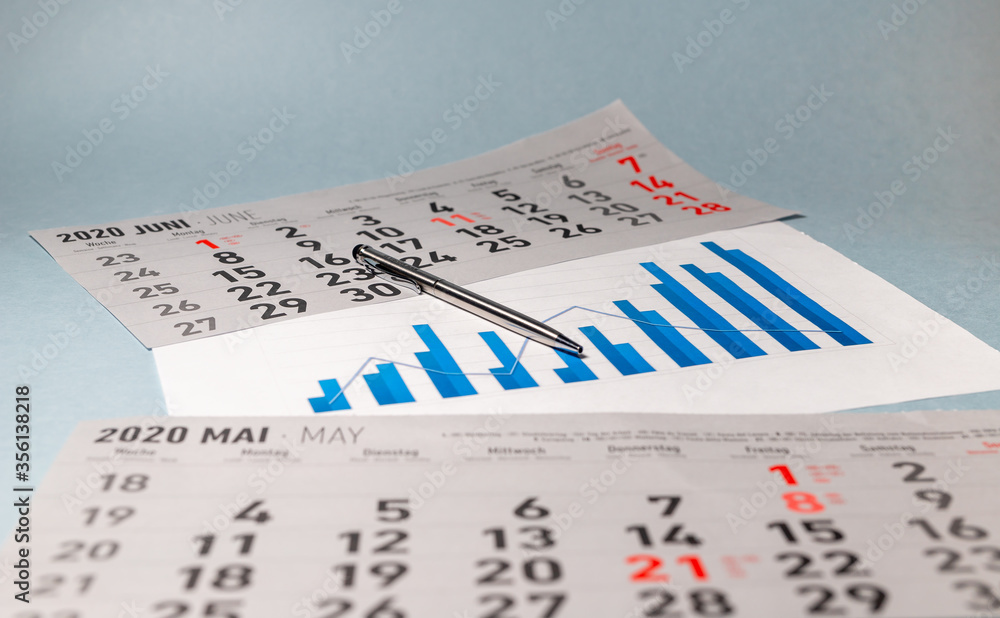 Poster silver pen on chart graph diagram of growth in blue color colour with calendar sheets on blue table.