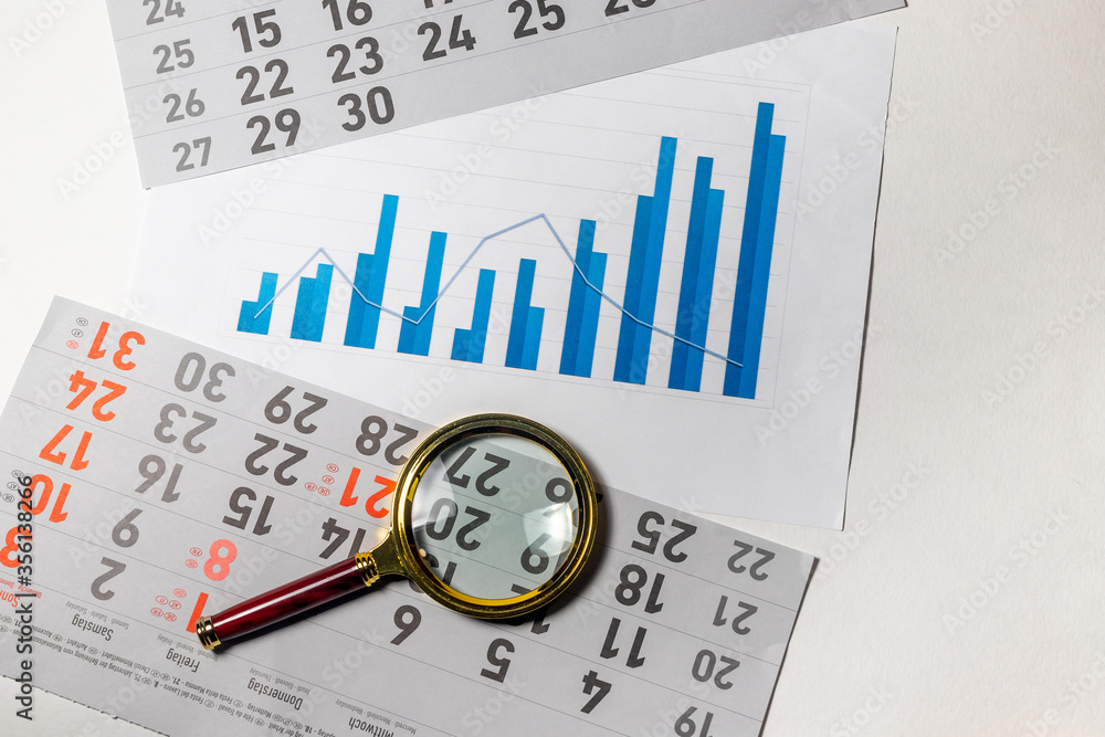 Poster golden magnifier on chart graph diagram of growth in blue color colour with calendar sheets on blue 