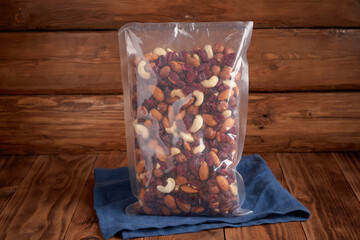 Organic dried fruits - a mixture of nuts and dried cranberries in a package against the background of texture design and linen textiles. Vegetarian food.