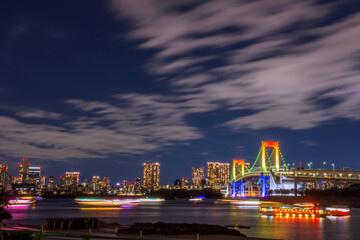 Obraz premium Odaiba, Tokyo, Beautiful and colorful rainbow bridge and Tokyo city night background image, cloudy in motion and left copy space for Title.