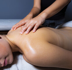 Close up of a woman relaxing on a lounger enjoys a massage in a wellness center