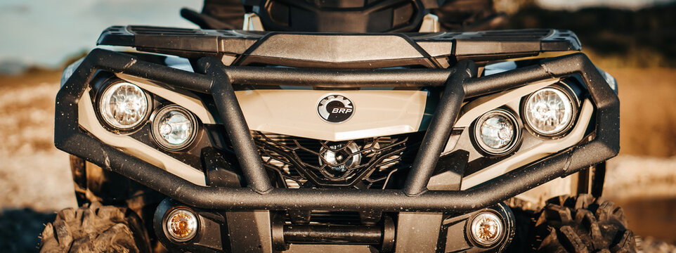 Banner detail close up of army green can-am outlander atv quad motorcycle bike's front light. It look's like very aggressive and strong off - road vehicle.