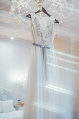 White wedding dress hanging on a chandelier