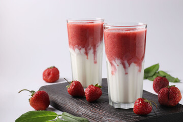Two servings of homemade smoothies with fresh strawberries, mint and yogurt in glasses on white background, Diet and weight loss control concept, Closeup