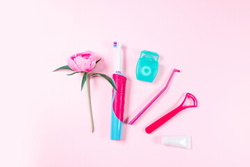 Ultrasonic pink toothbrush, dental floss and mouthwash and tongue cleaning on a pink background
