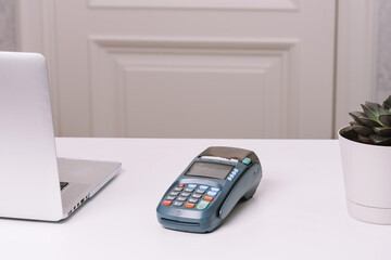 NFC payment terminal on a white table. Credit card or phone pay pos banking device, card machine.